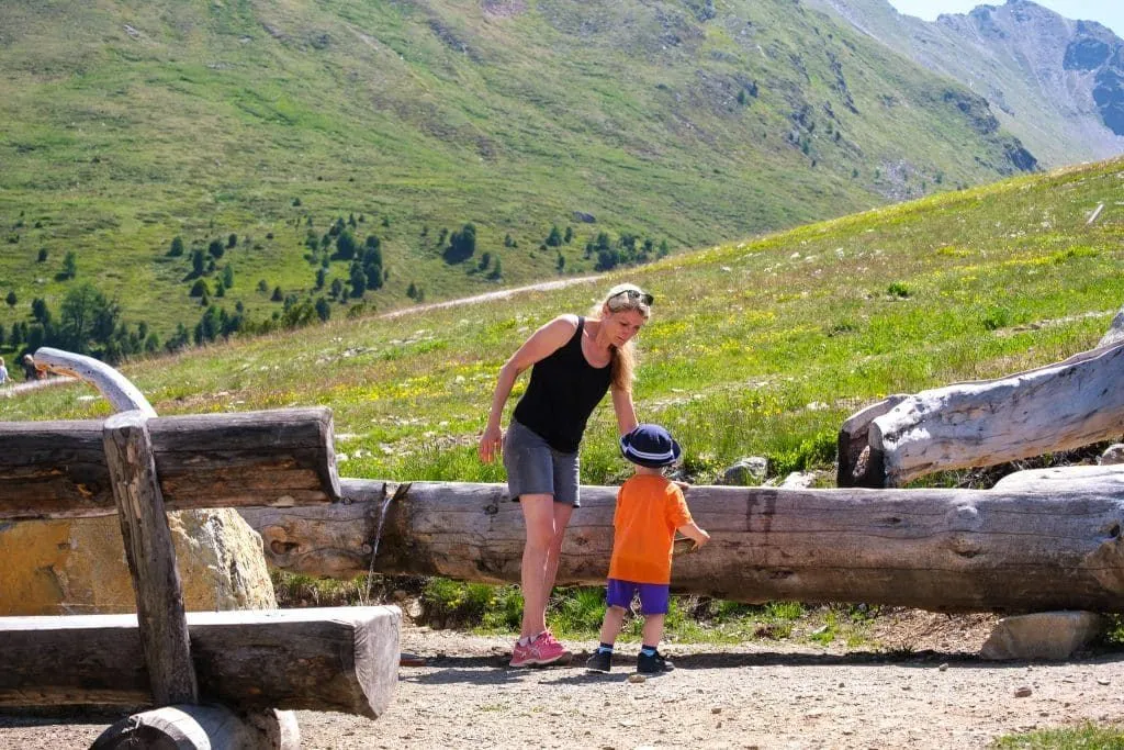 Mutter und Kind an einem Holzbalken auf der Alm