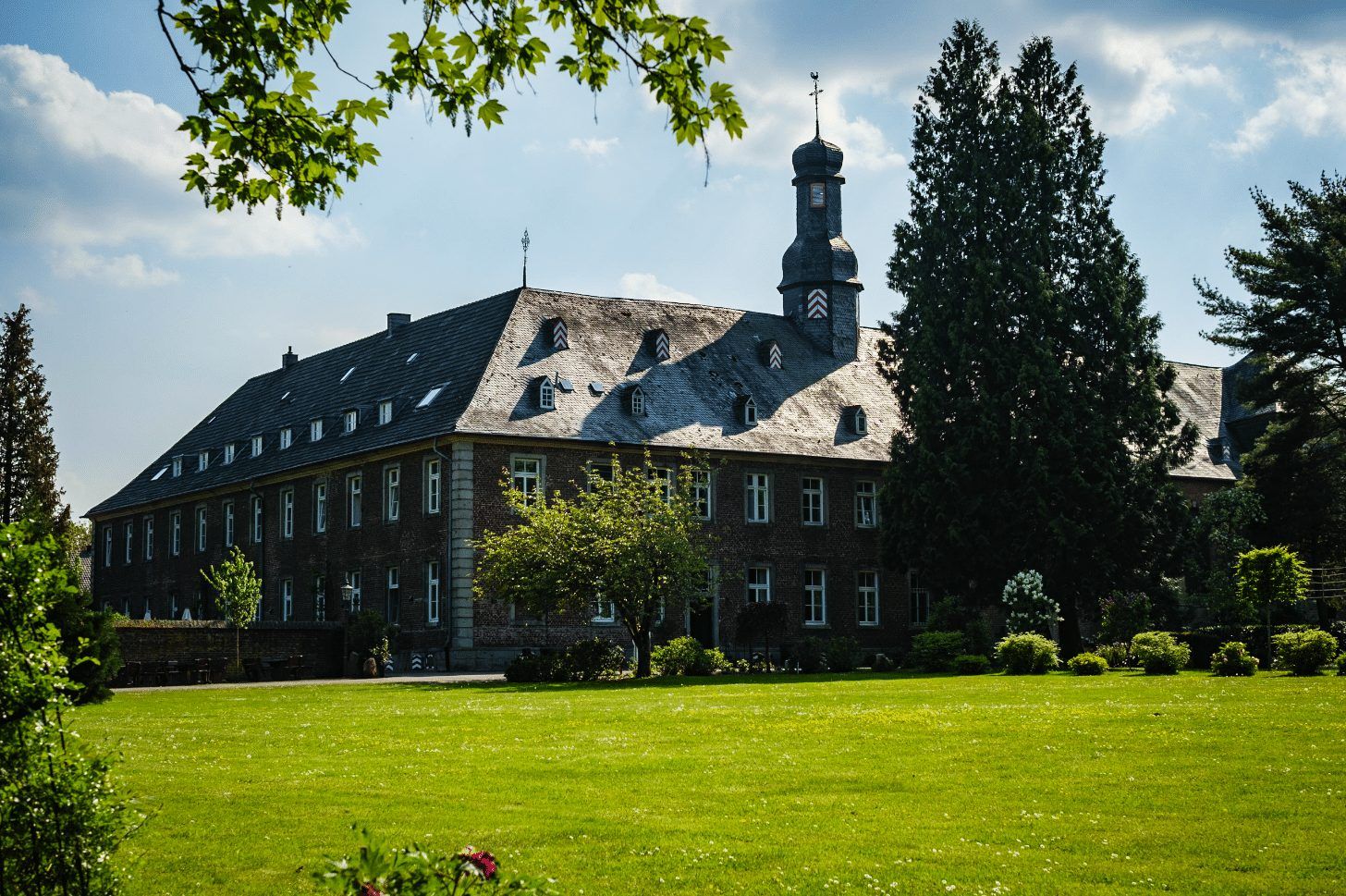 Das Nikolauskloster mit Rasen und Bäumen unter blauem Himmel