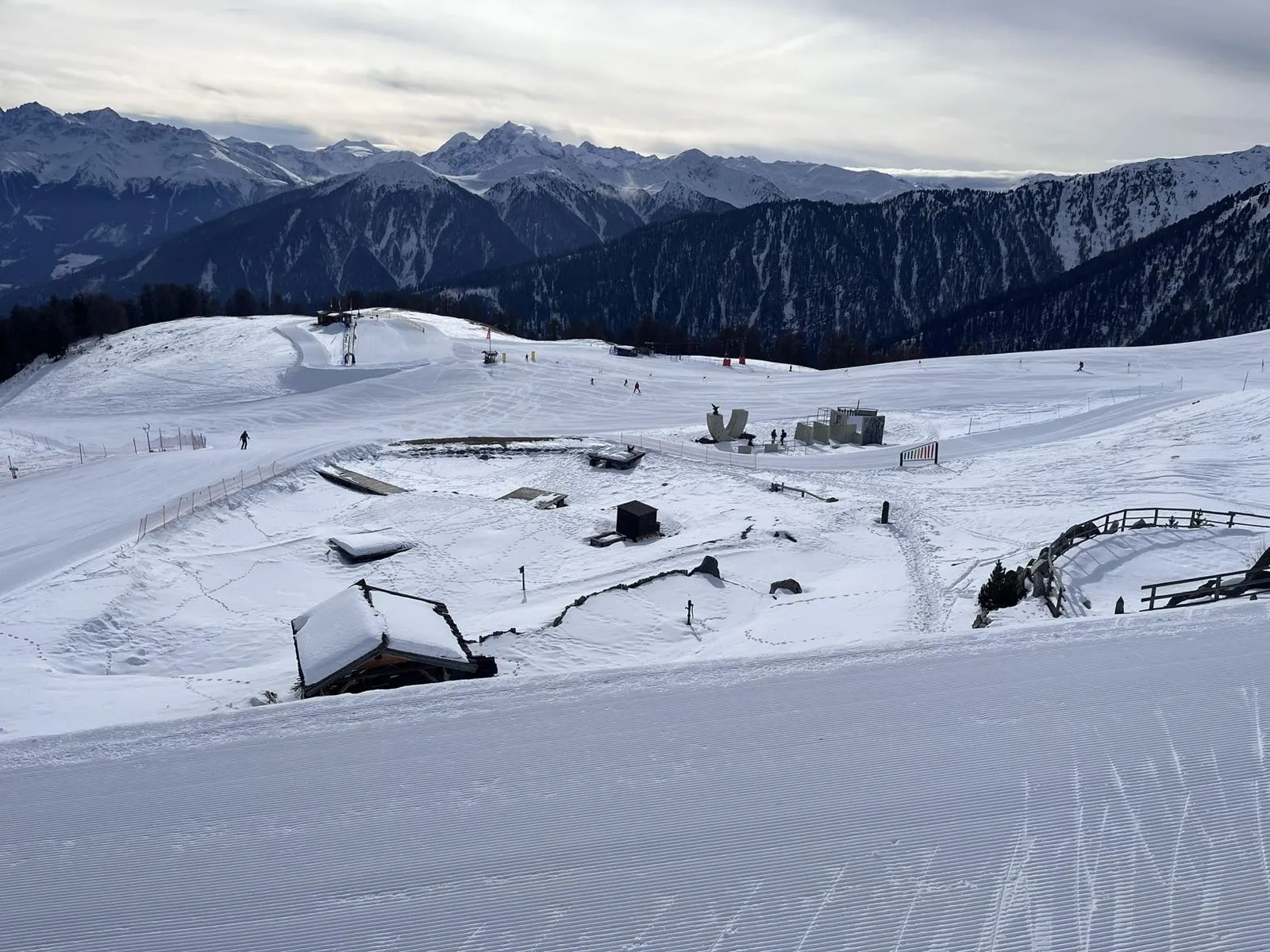 Blick von oben auf den verschneiten Kinderpark am Watles, dahinter die Berge des Vinschgaus