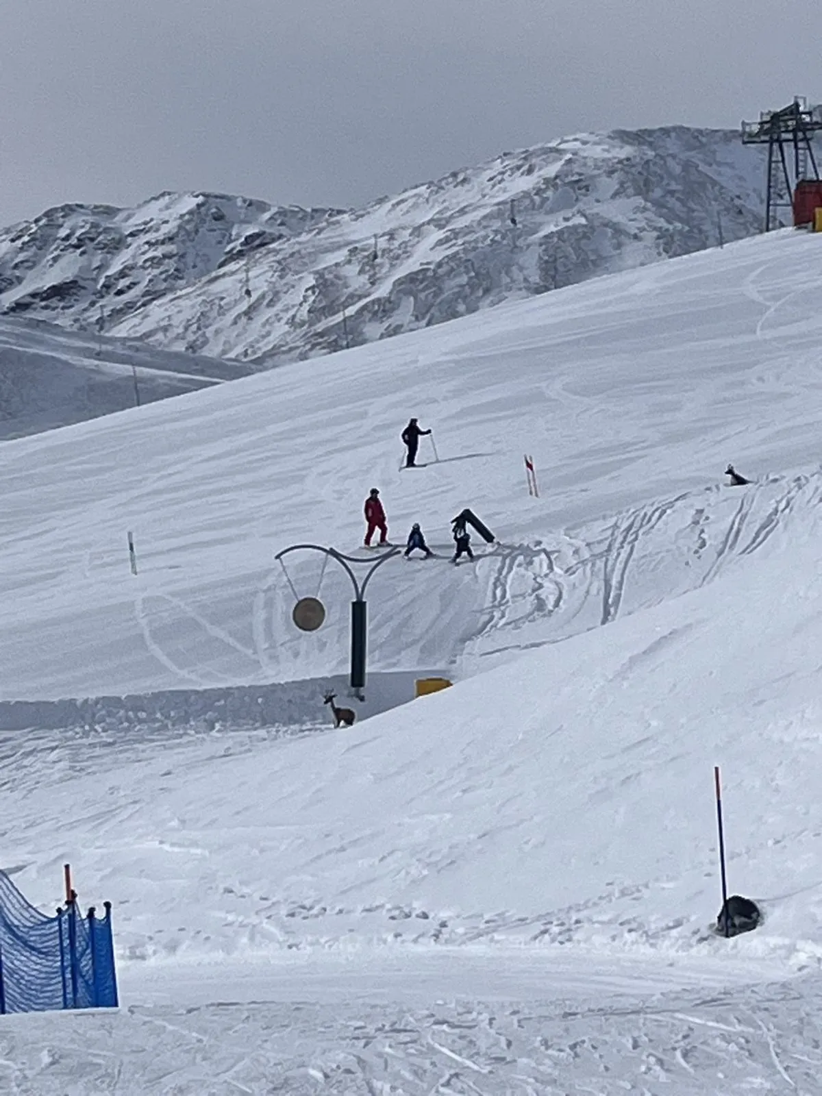Skilehrer übt mit zwei kleinen Kindern im Kinderpark, daneben ein Gong und eine Rehfigur