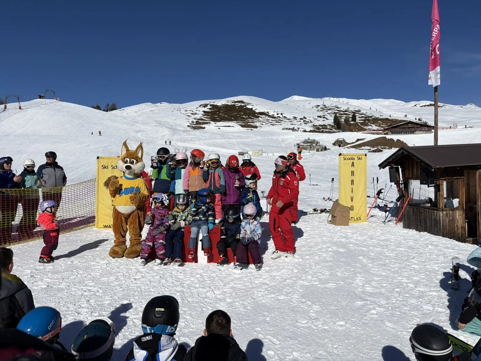 Siegerehrung der Skischule Watles: Kinder mit Pokalen auf dem Podest, daneben das Maskottchen Bubo