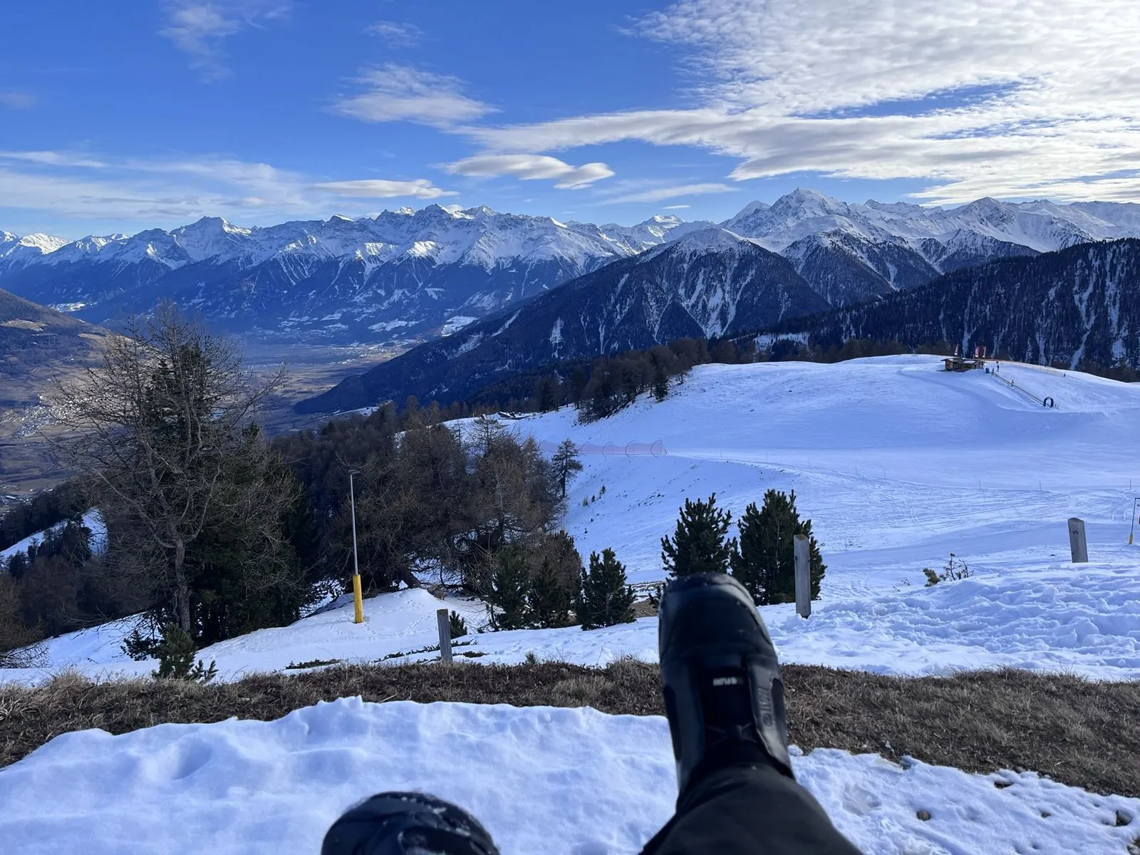 Blick von einer Bank am Watles über den Übungshang ins Vinschgau, im Vordergrund Winterstiefel