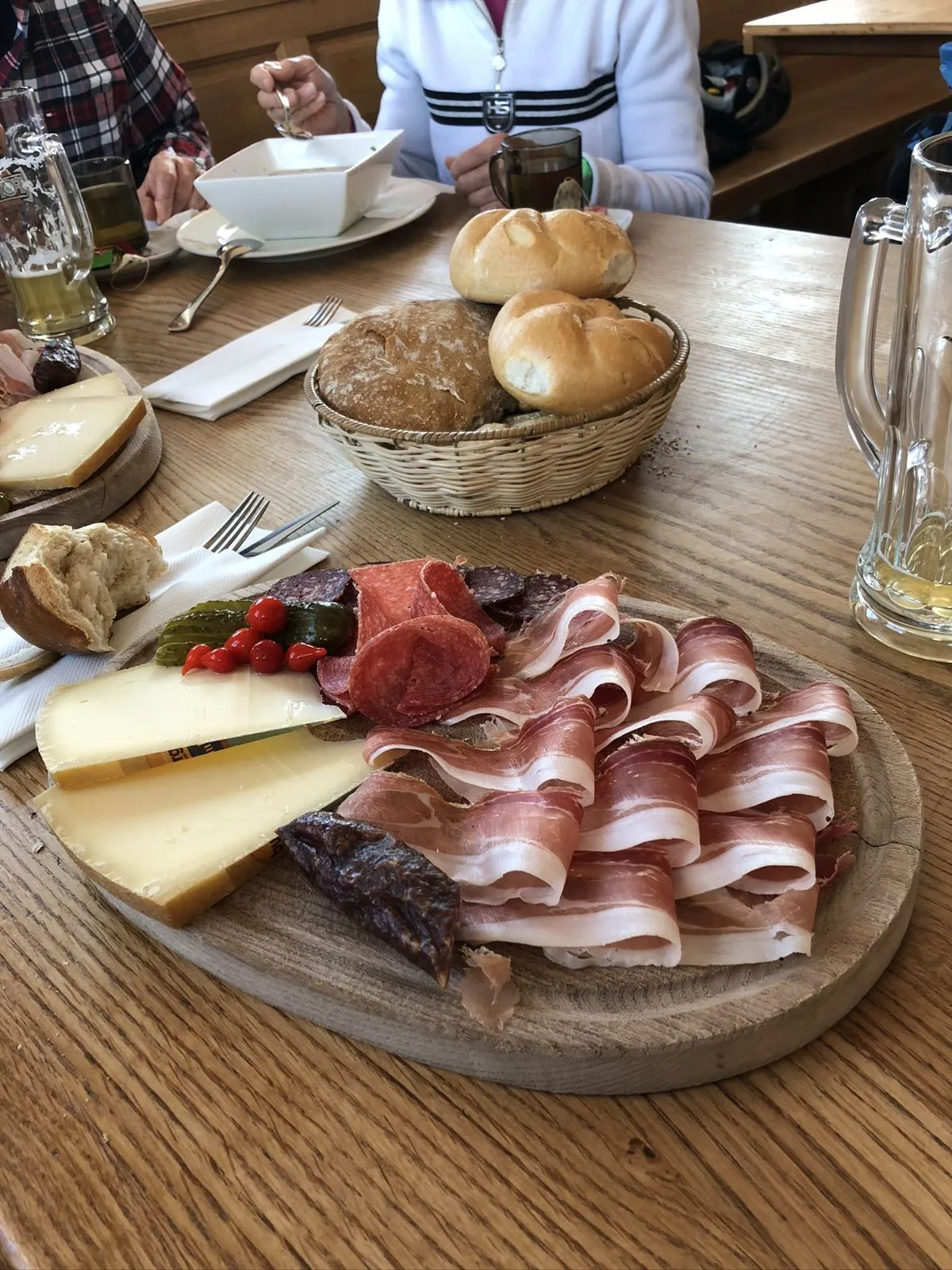 Brettljause mit Speck, Kaminwurz und Käse, dahinter ein Brotkorb