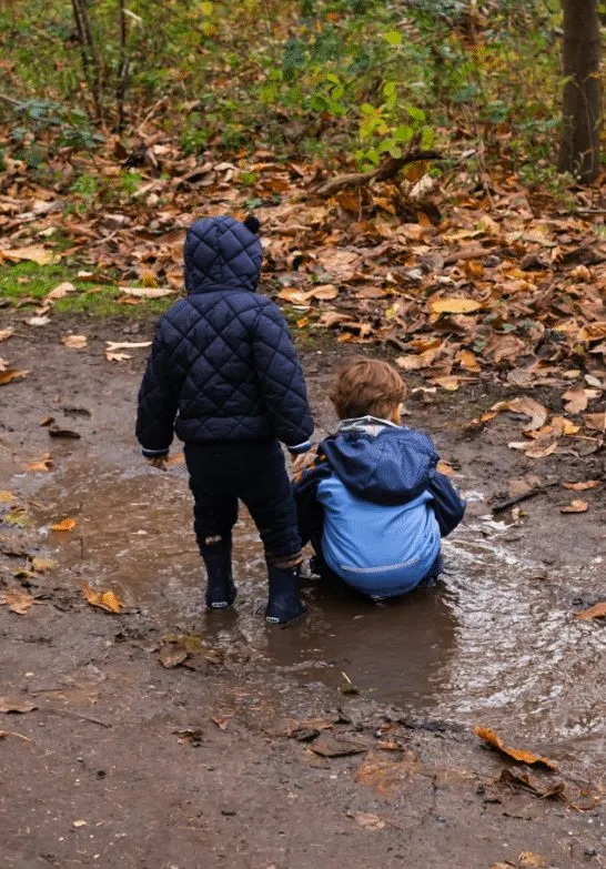 Zwei Kinder in einer Pfütze im Herbstwald
